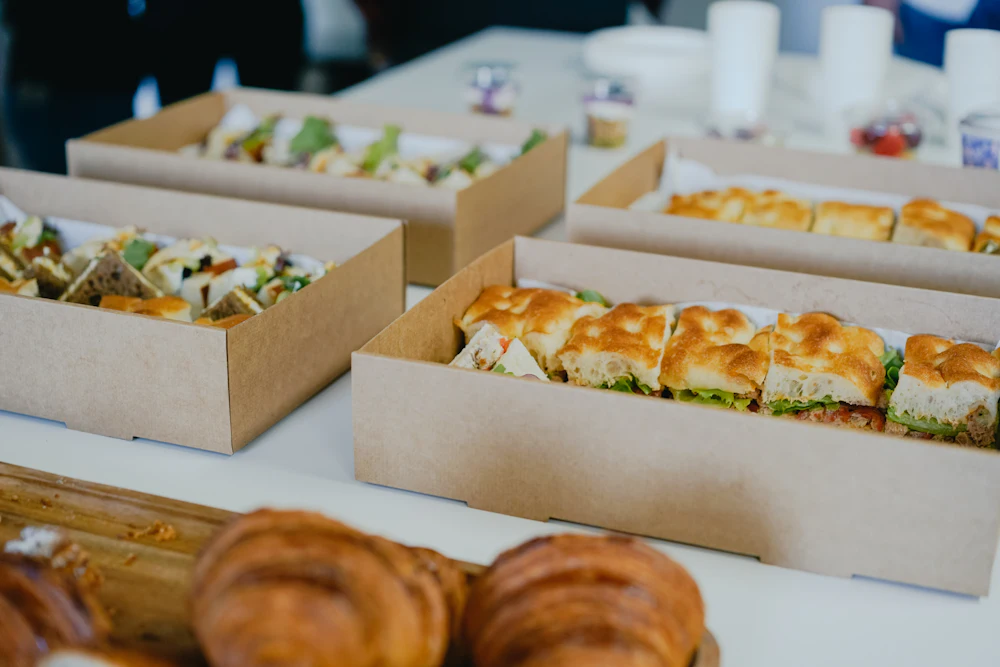Boxes of sandwiches and pastries laid out for an office lunch